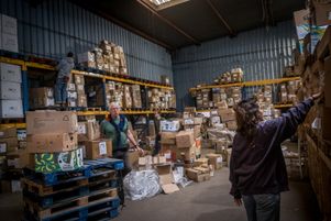 Des bénévoles font le tri dans l’entrepôt de stockage de l'auberge des migrants où sont regroupées plusieurs associations, le 12 novembre 2021.