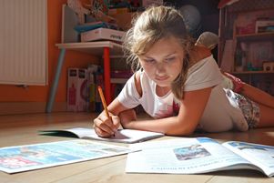 À Ingersheim, une jeune fille fait ses devoirs de vacances dans sa chambre avec le Journal des enfants.