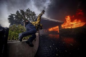 Un pompier californien saute une clôture devant une villa en feu dans le quartier de Pacific Palisades, où les incendies ont démarré mardi 7 janvier.