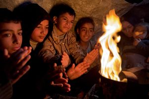 Des Palestiniens dans des tentes de fortune essaient de se réchauffer autour d’un feu alors qu’ils luttent contre les pluies et le froid à Khan Yunès, Gaza, le 7 mars 2025.